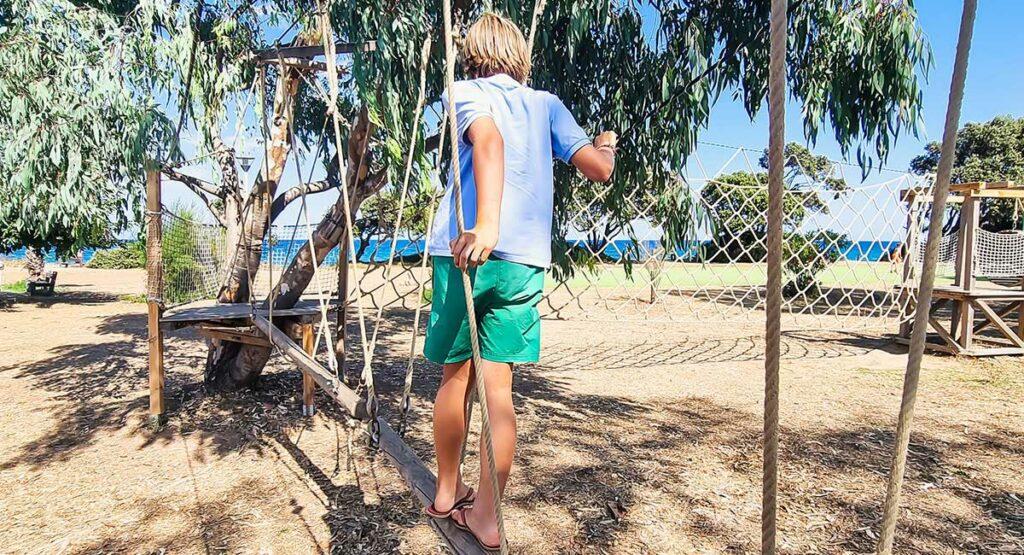Kind auf dem Seilparcours am Spielplatz des Campingplatzes Le Campoloro auf Korsika