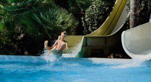 Child splashing down from a slide, campsite water park in Corsica