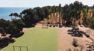 Terrain de football entre pinède et mer vu du ciel, camping sportif en Corse