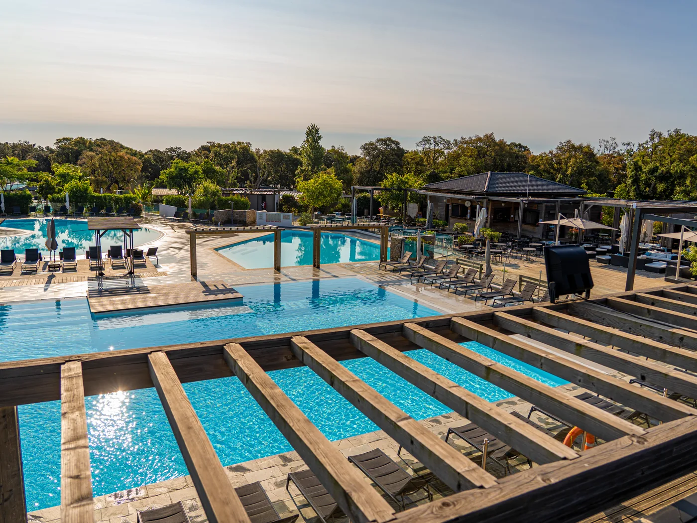 Piscines et pergola en bois du camping Le Campoloro en fin de journée